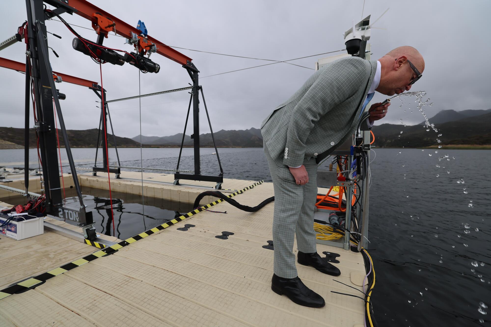 A man tastes water flowing from a spigot on a dock
