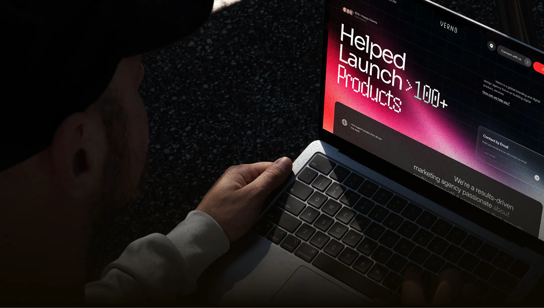 Person using a laptop displaying a website with the headline 'Helped Launch >100+ Products' in white and red text.