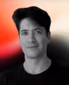 Portrait of a young man with dark hair wearing a black shirt against a gradient background.