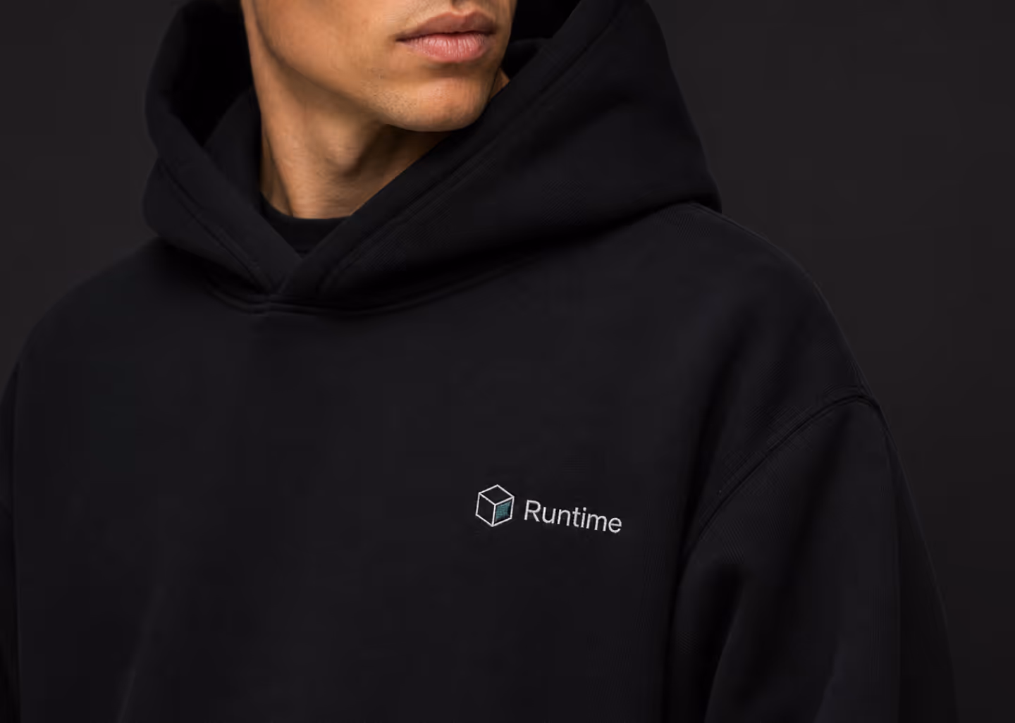Person wearing a black hoodie with Runtime logo embroidered on the chest.