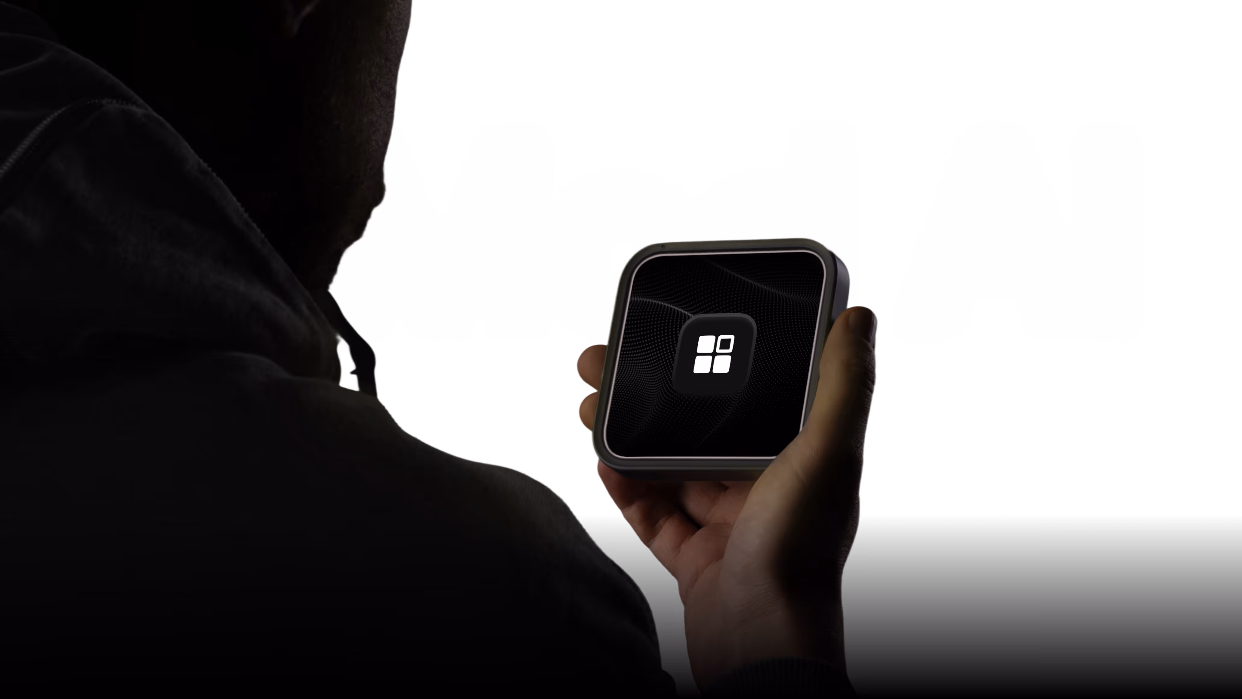 Person holding a small square device with a black screen showing a white logo in the center.