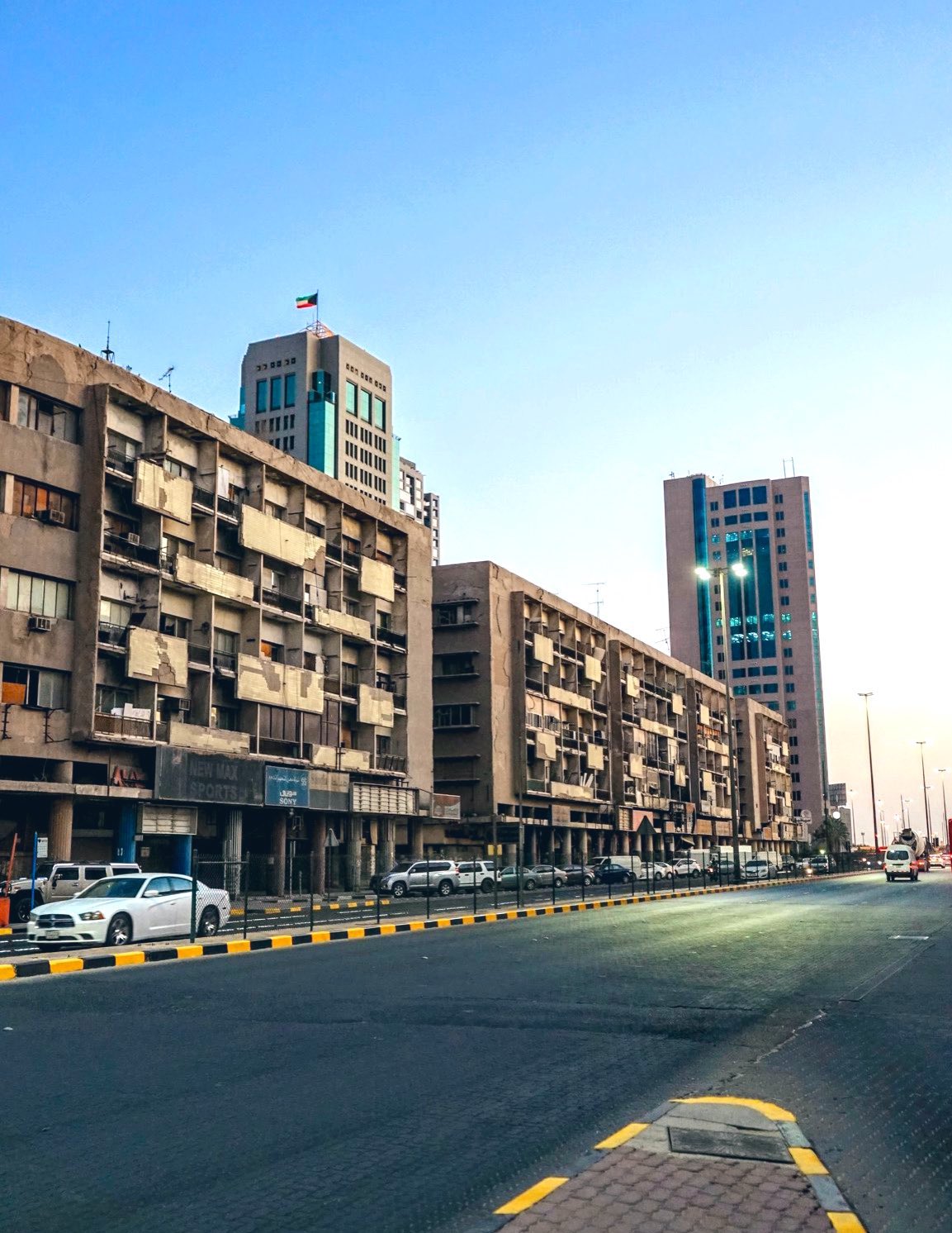 Urban street with mid-rise buildings, parked cars, and clear sky—capturing everyday life and architecture in a Middle Eastern city.