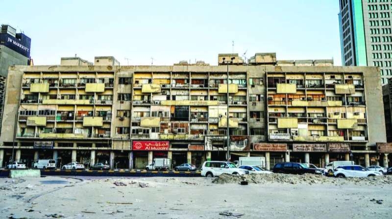 Aged multi-story building with shops, balconies, and satellite dishes, reflecting dense urban life and architectural adaptation.