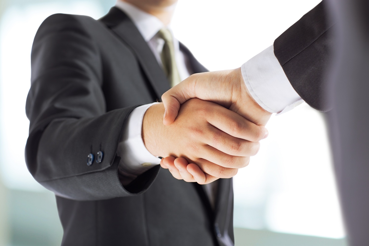 Close-up of two professionals in suits shaking hands, symbolizing trust, partnership, and successful business agreement.