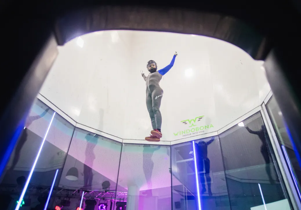 Person standing upright mid-air inside a vertical wind tunnel
