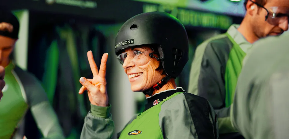 Woman in skydiving gear making peace sign