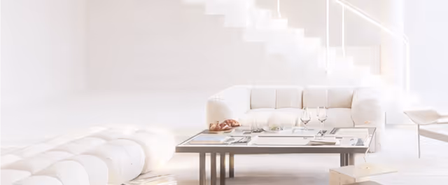 Bright, modern living room with white sofa, rectangular glass coffee table set for dining, and white stairs in background.