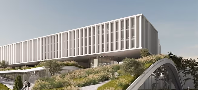 Modern building with tall vertical columns elevated above green landscaping and trees.