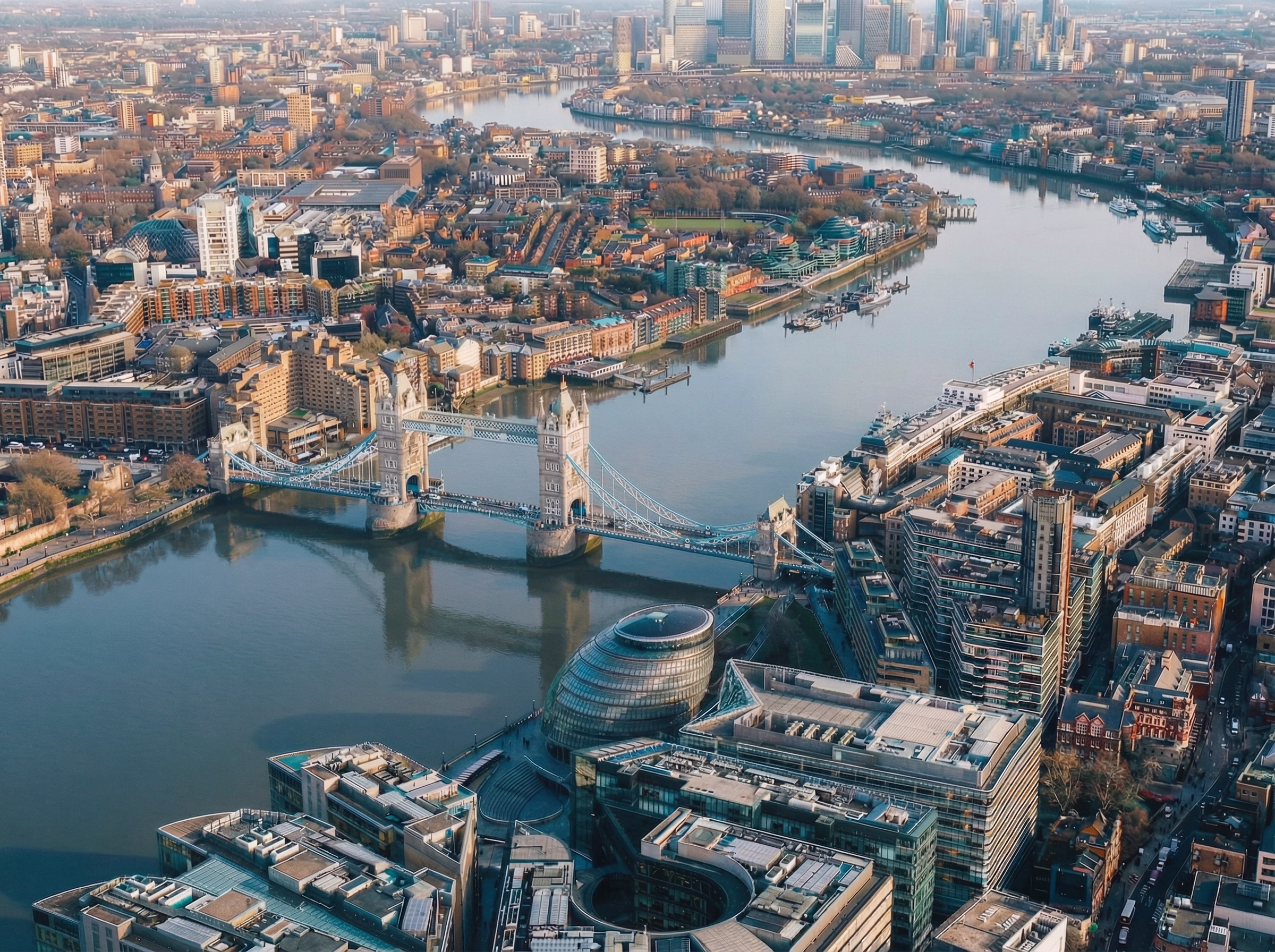 Aerial view of Tower Bridge over the River Thames with City Hall and Canary Wharf skyline in the background in London.