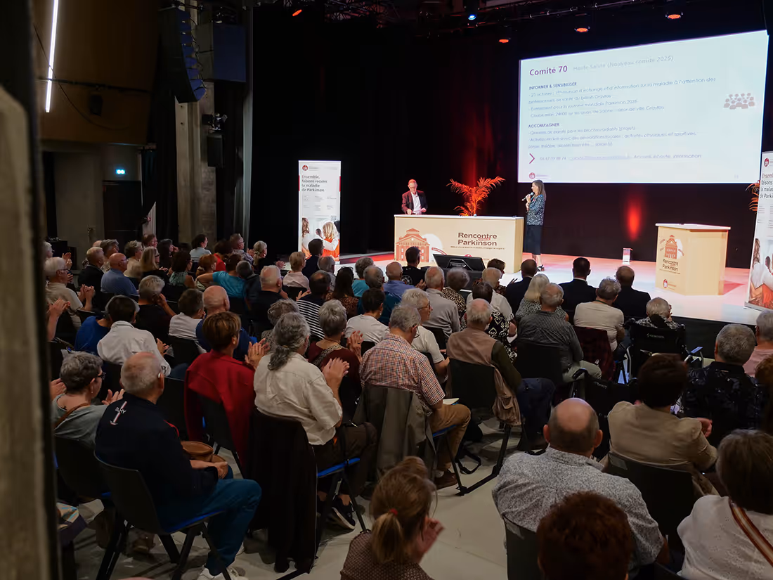 Conférence sur la maladie de Parkinson réunissant un large public, animée par deux intervenants sur scène, dans un cadre professionnel et engagé.