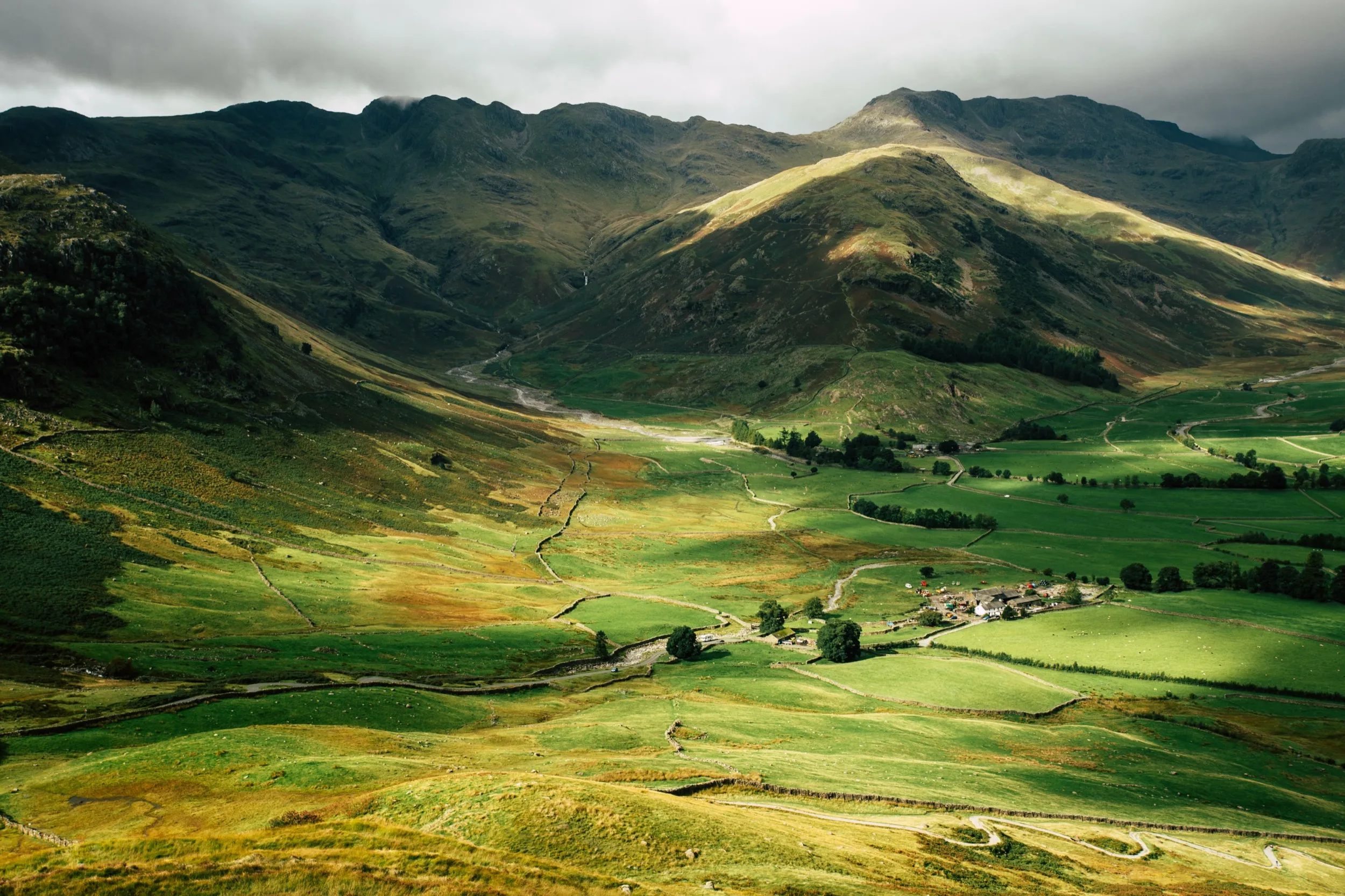 Dramatic mountain landscape with green valley and small village nestled below