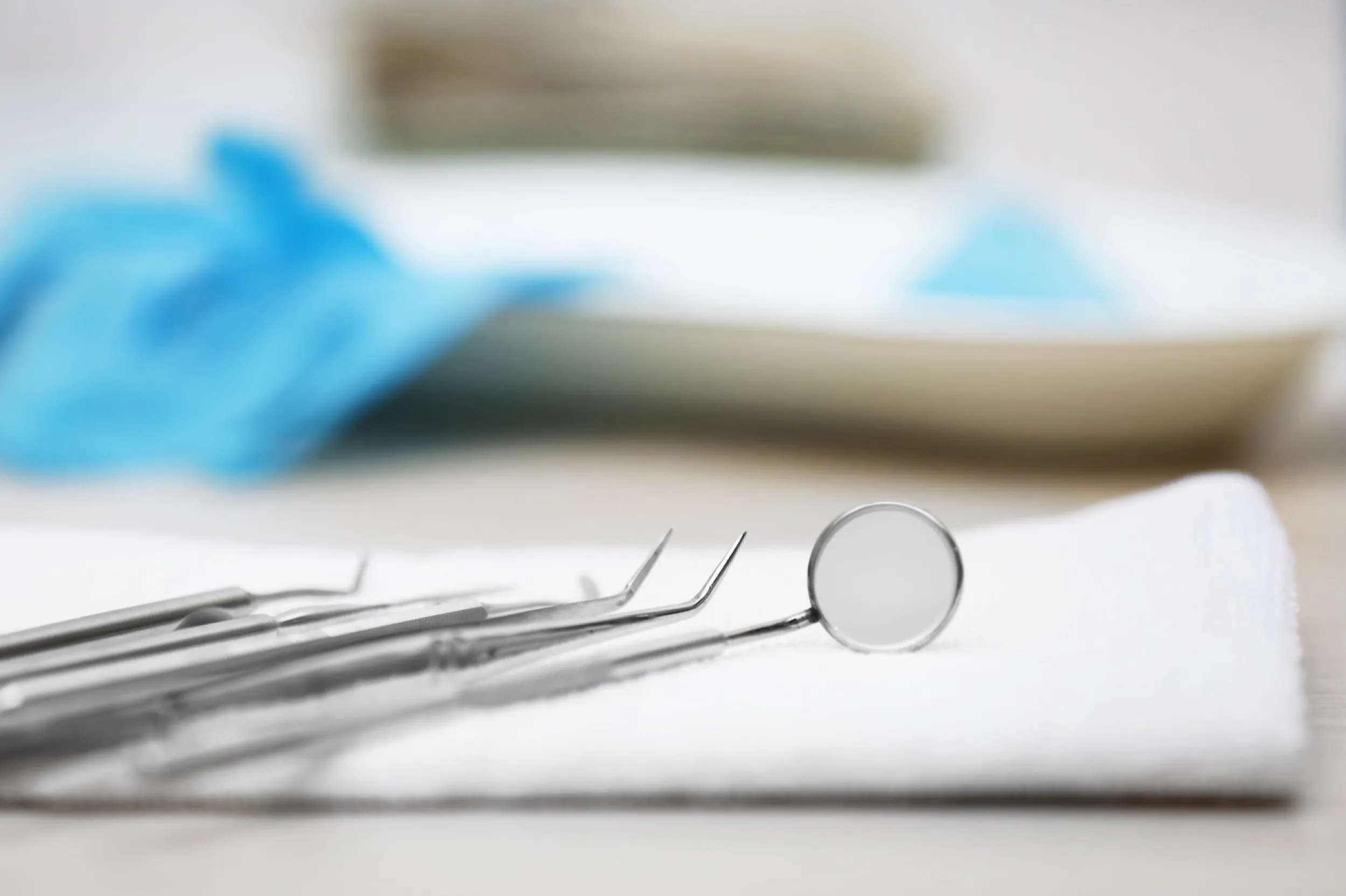 Dental tools and mirror on white towel with blue surgical cloth