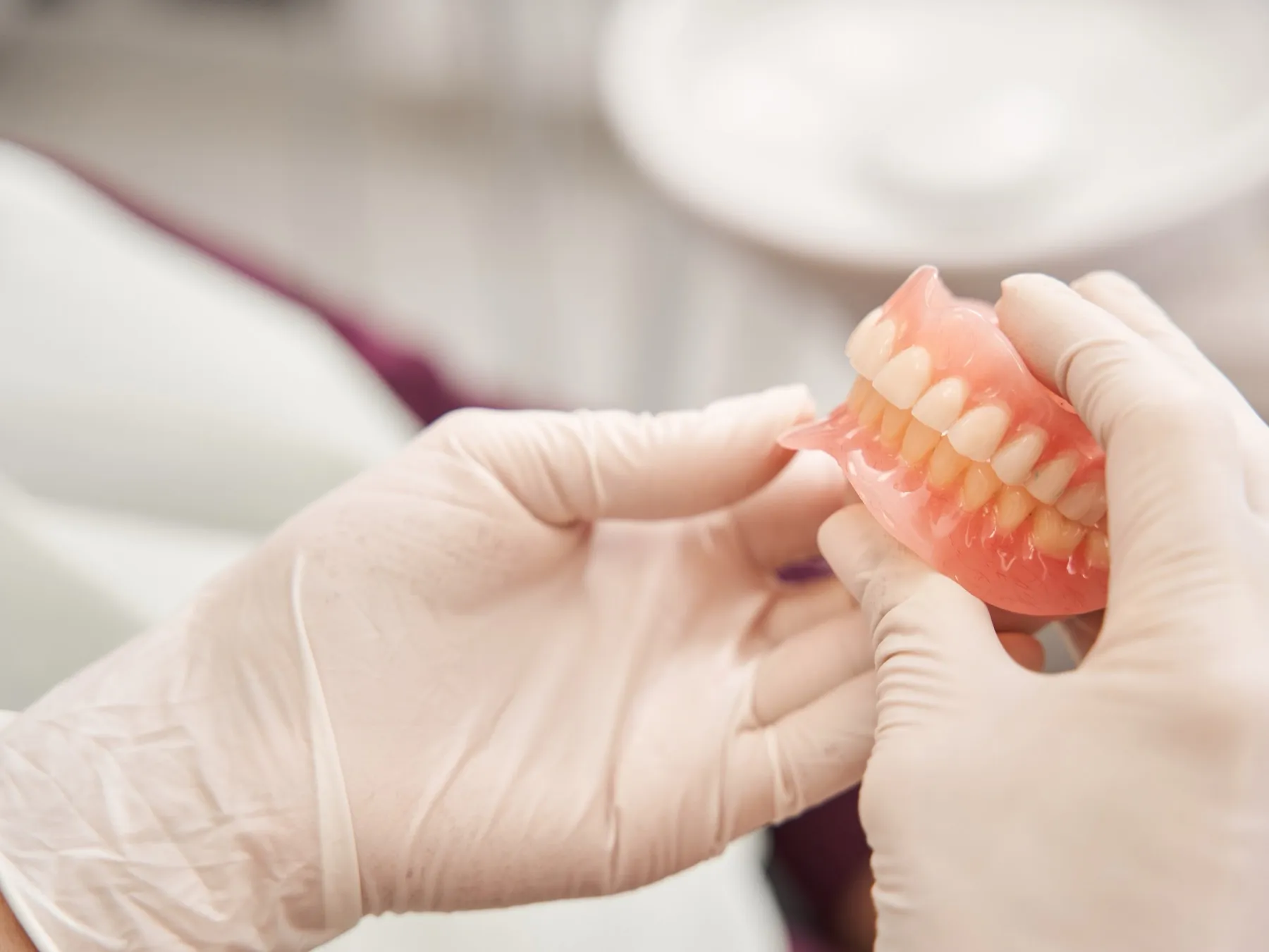 Dentist hands in gloves holding pink complete dentures