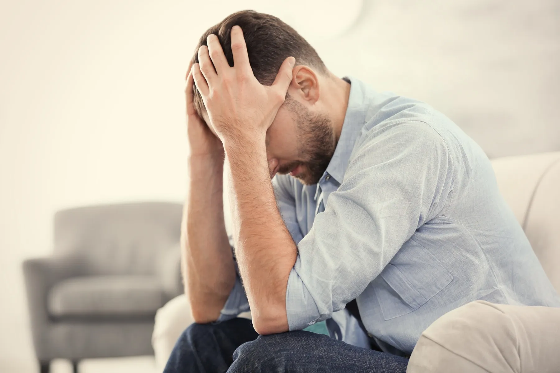 Person sitting on couch, head in hands, expressing distress or frustration