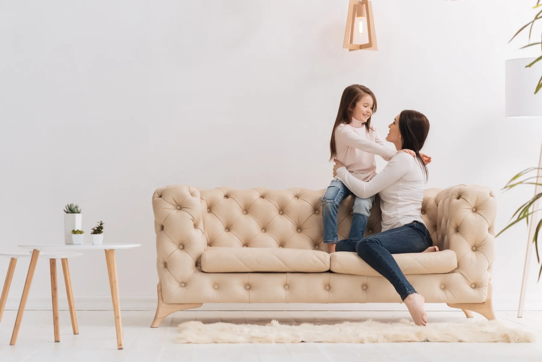 Parent and child hugging on tufted couch in minimalist living room