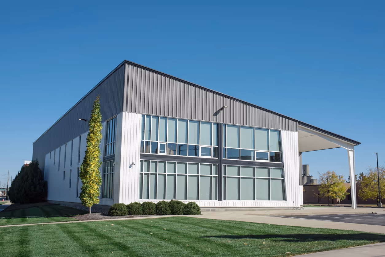 Modern white and gray office building with large windows and landscaped lawn