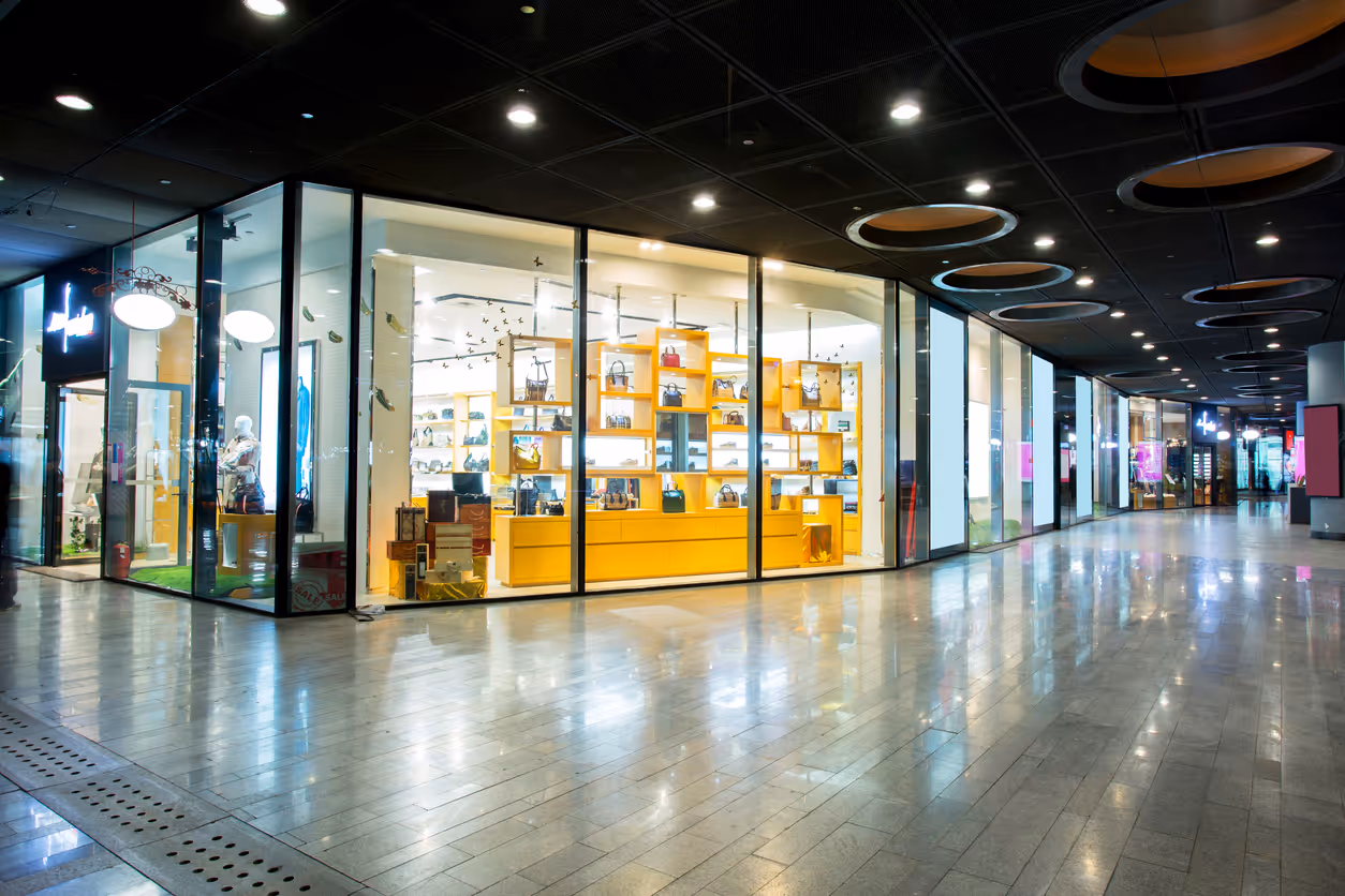 Modern shopping mall with bright yellow handbag store and glass storefront