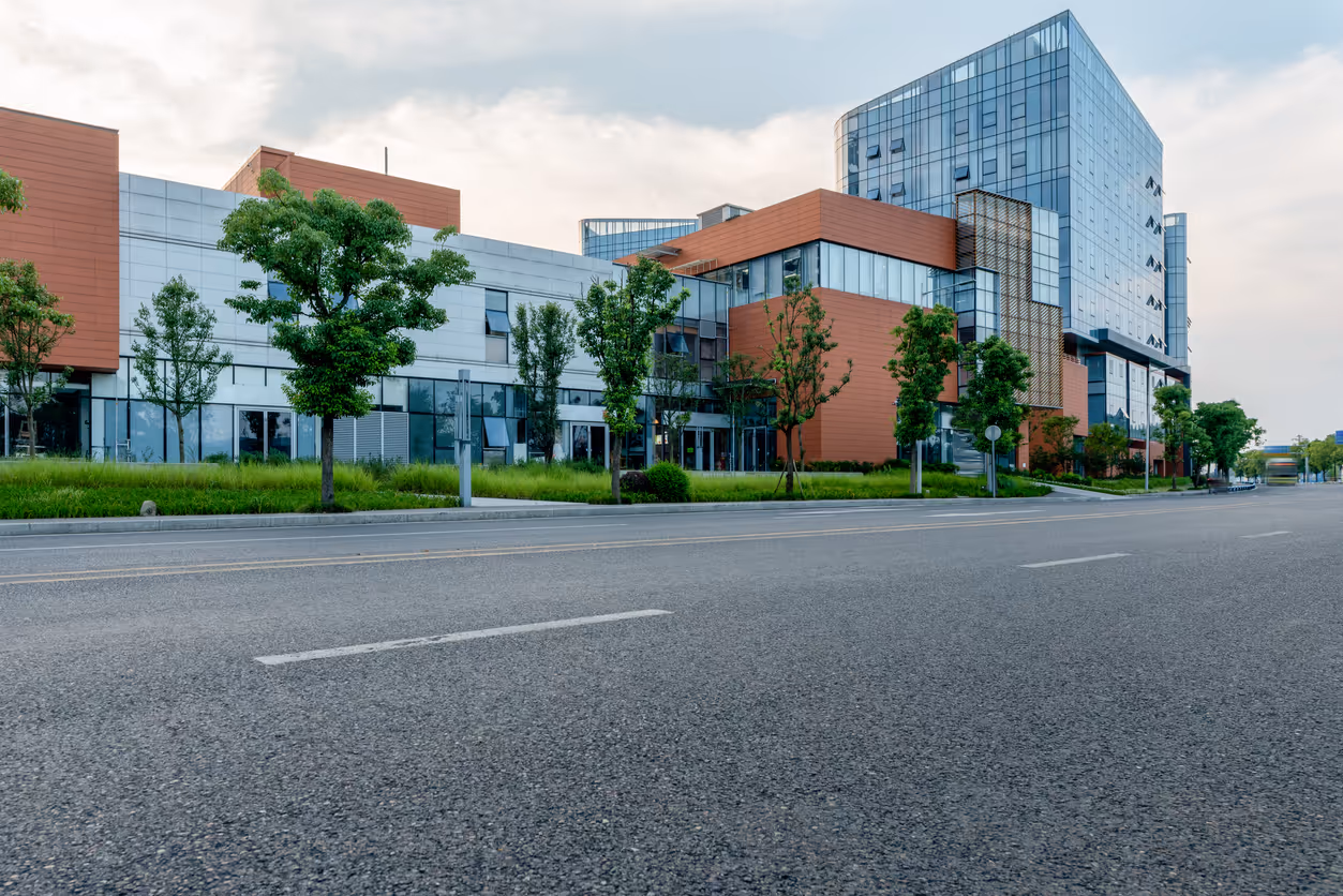 Modern glass and brick office buildings with trees along empty street