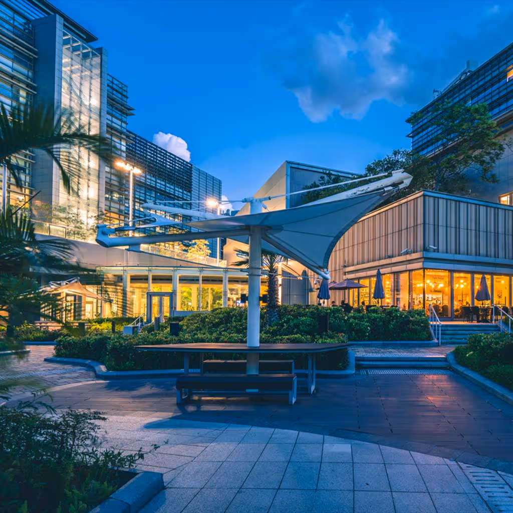 Modern glass buildings with outdoor seating area at blue hour