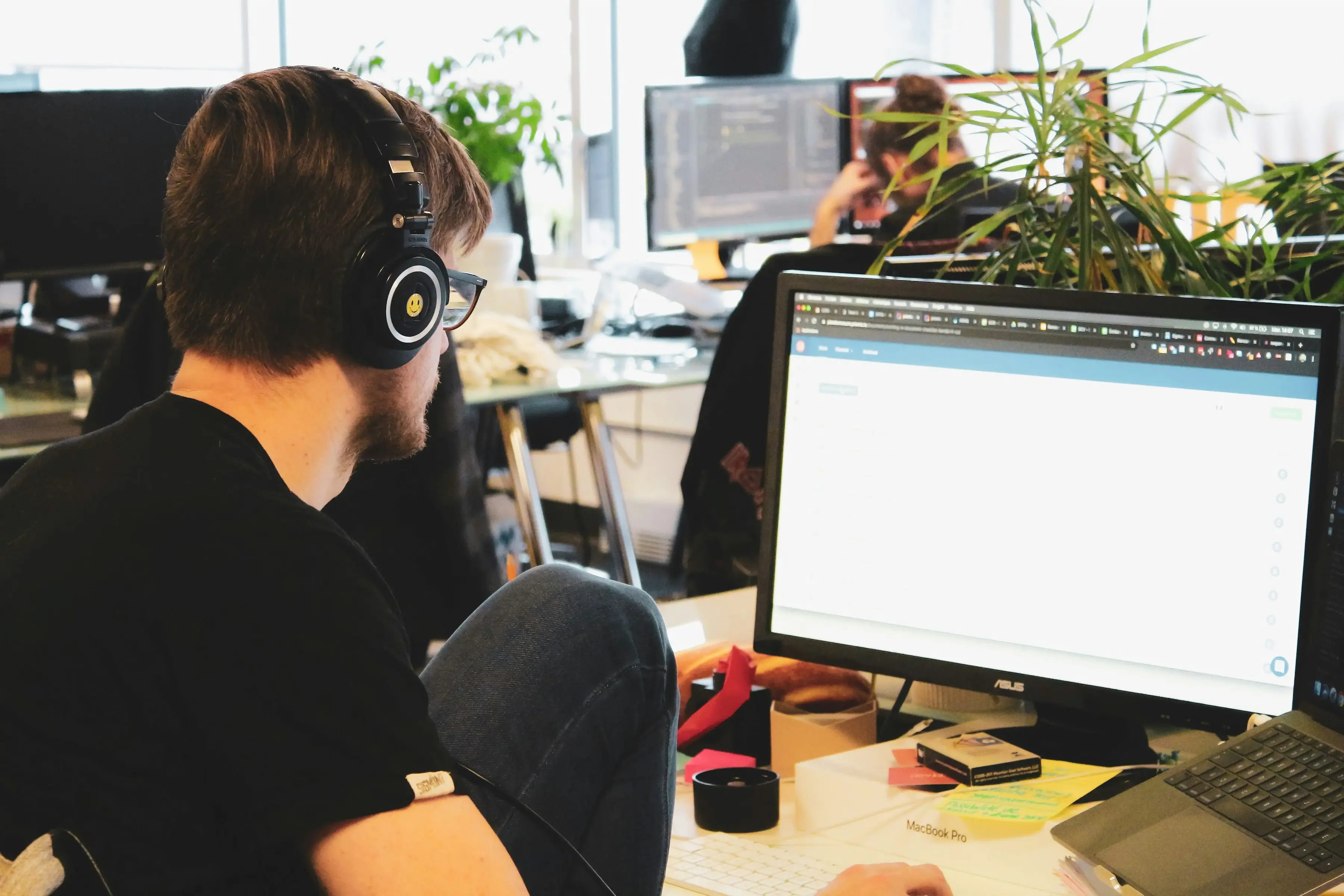 Homme dans un bureau devant son ordinateur et portant un casque sur les oreilles