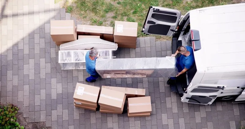 A couple of men unloading boxes from a truck.