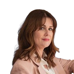 Woman with shoulder-length brown hair wearing a light pink blazer and white blouse, looking ahead.