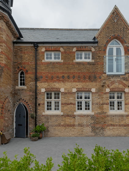 Restored Victorian coach house exterior with arched brick doorway and gothic windows at Trent Park, Enfield