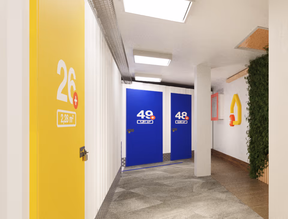 Pasillo de trasteros AticPlus con puertas amarillas y azules.