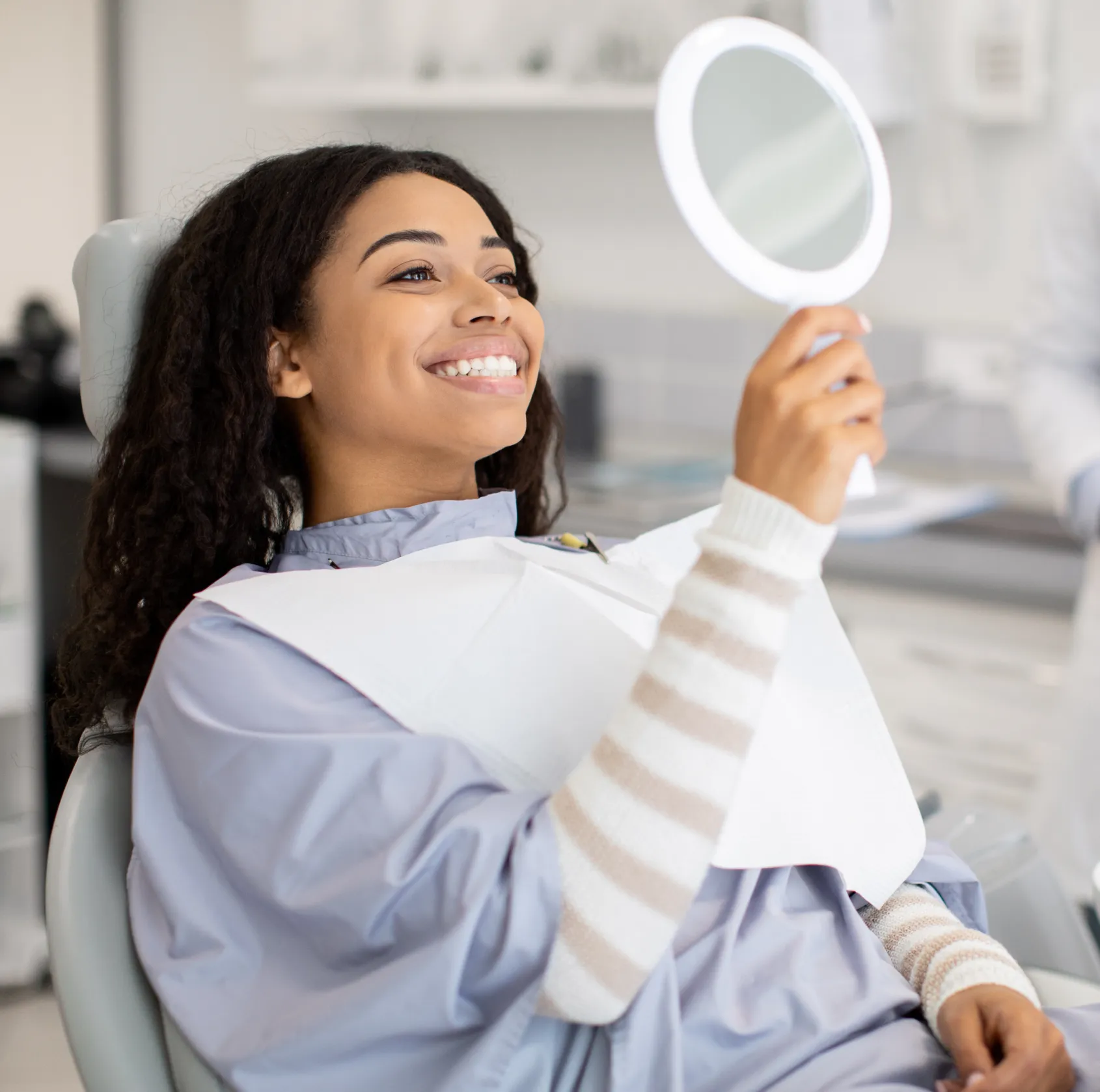 Happy patient looking at her new smile in the mirror