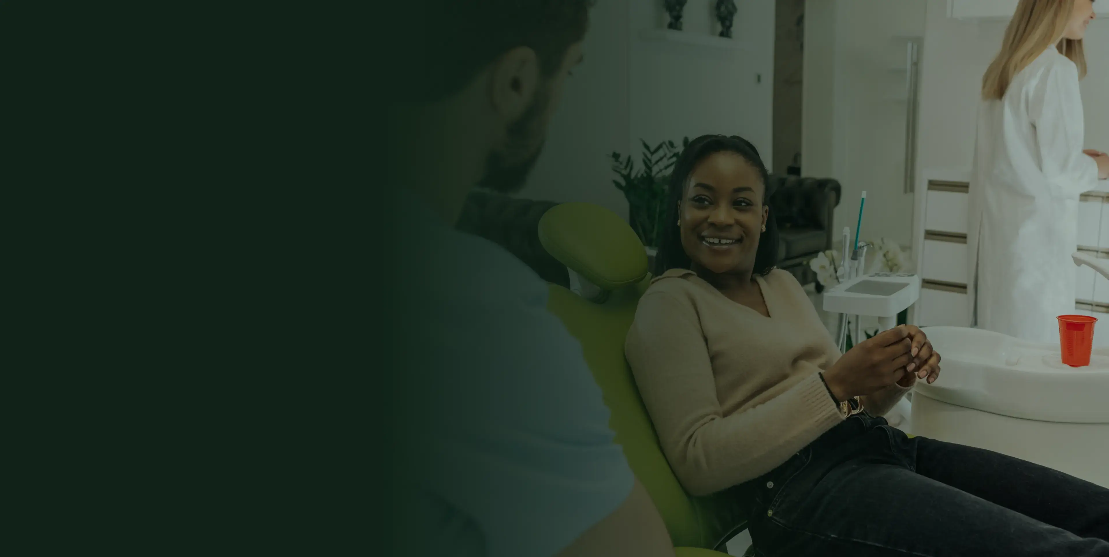 Woman sitting in a dental chair, smiling and talking to a man.