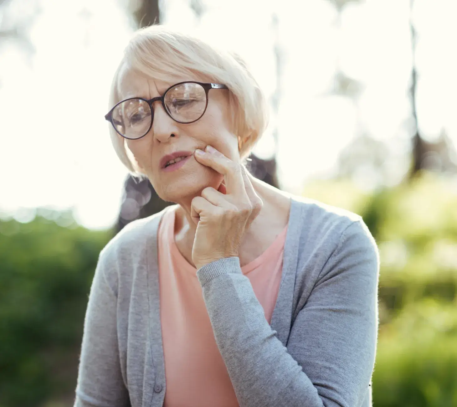 A smiling woman wearing a hat holds hands with a person partially visible in the background.