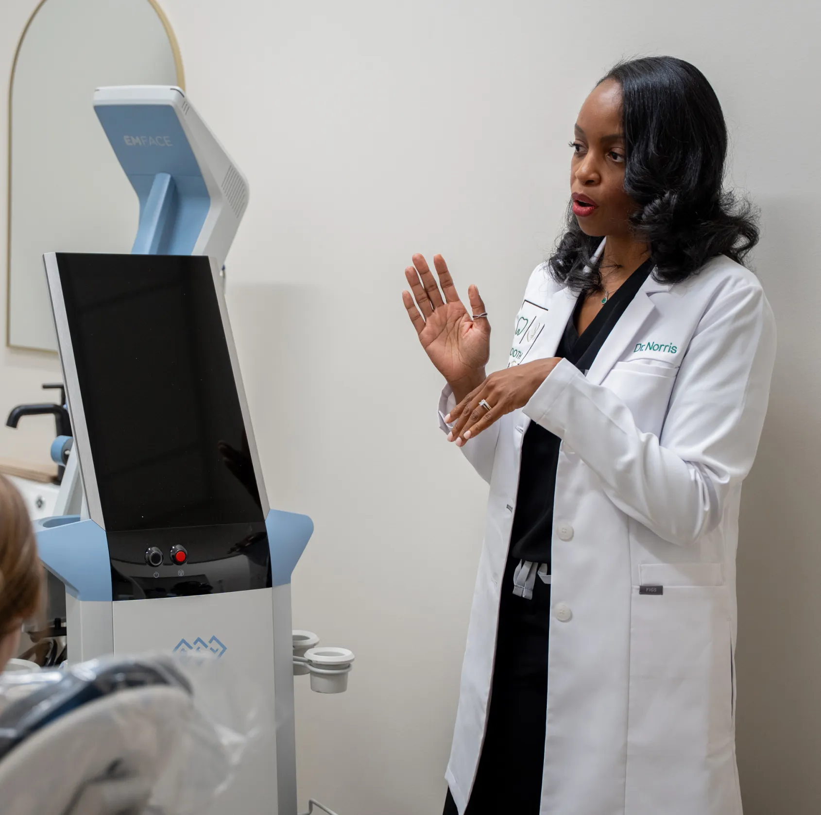 A doctor in a white coat explains a medical device to a patient.