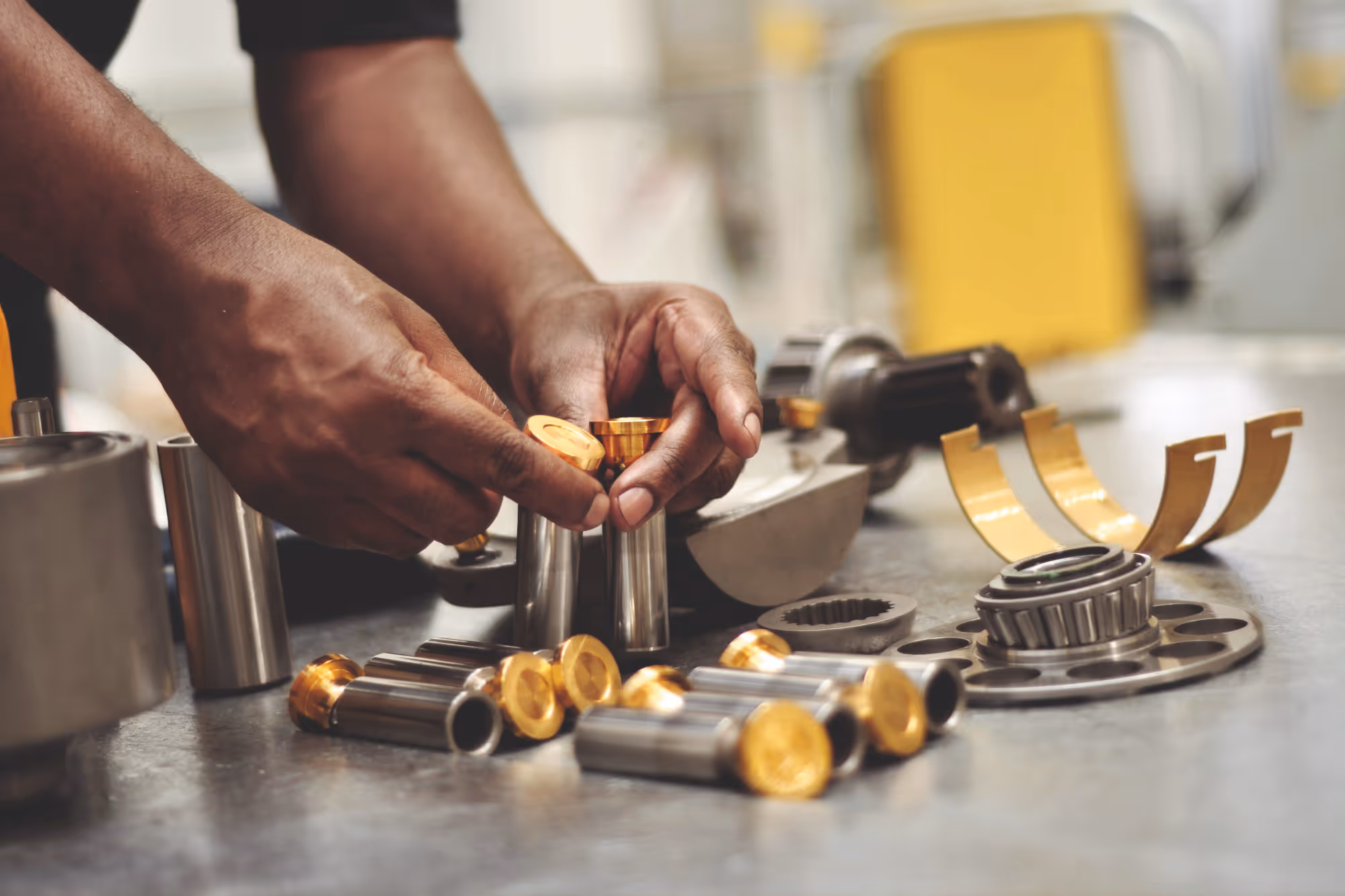 Handen die metalen onderdelen met gouden uiteinden op een tafel plaatsen in een werkplaats.