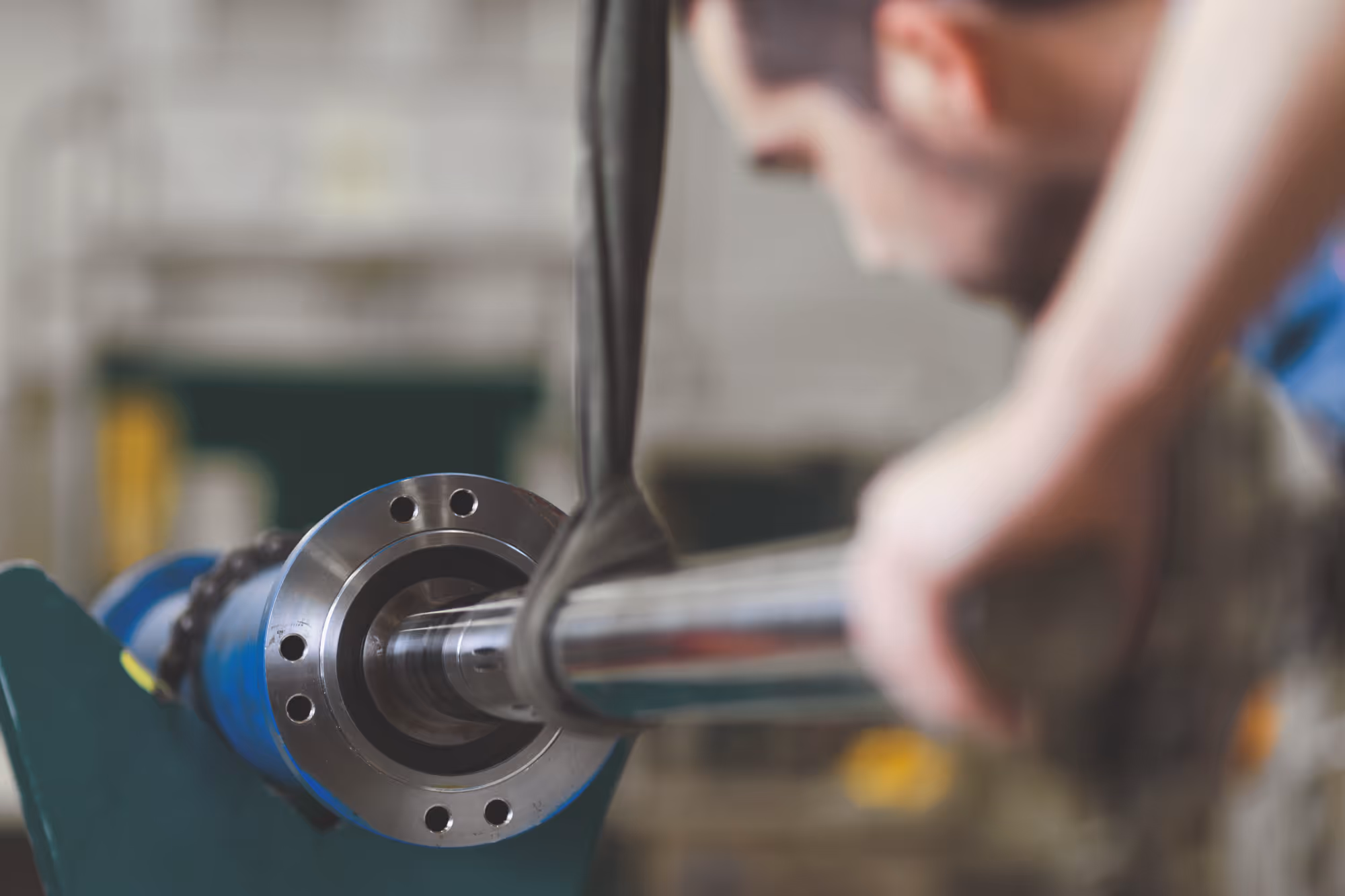 Man werkt met een metalen as in een fabriek of werkplaatsinstelling.