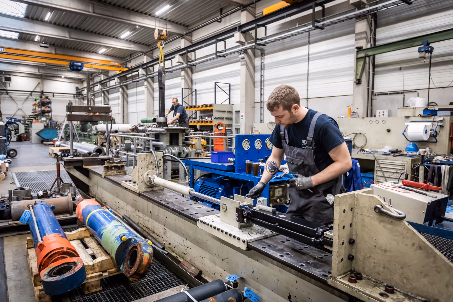 Technicus werkt aan een grote machine in een industriële werkplaats met gereedschap en apparatuur.
