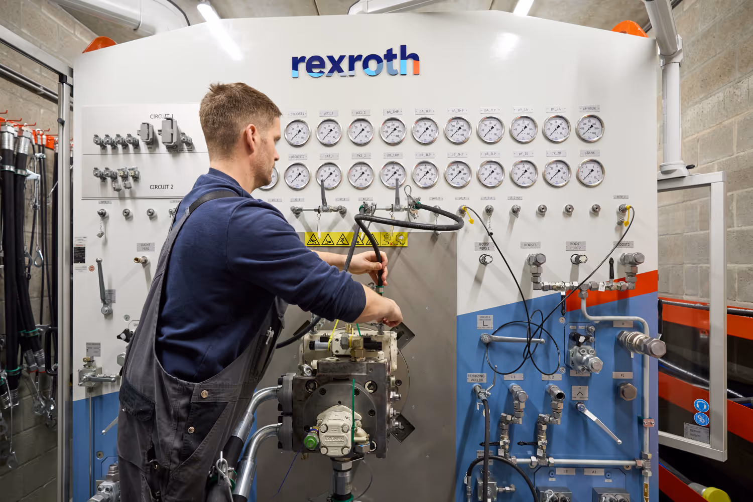 Technicus werkt aan een hydraulisch bedieningspaneel met meters en knoppen van Rexroth.