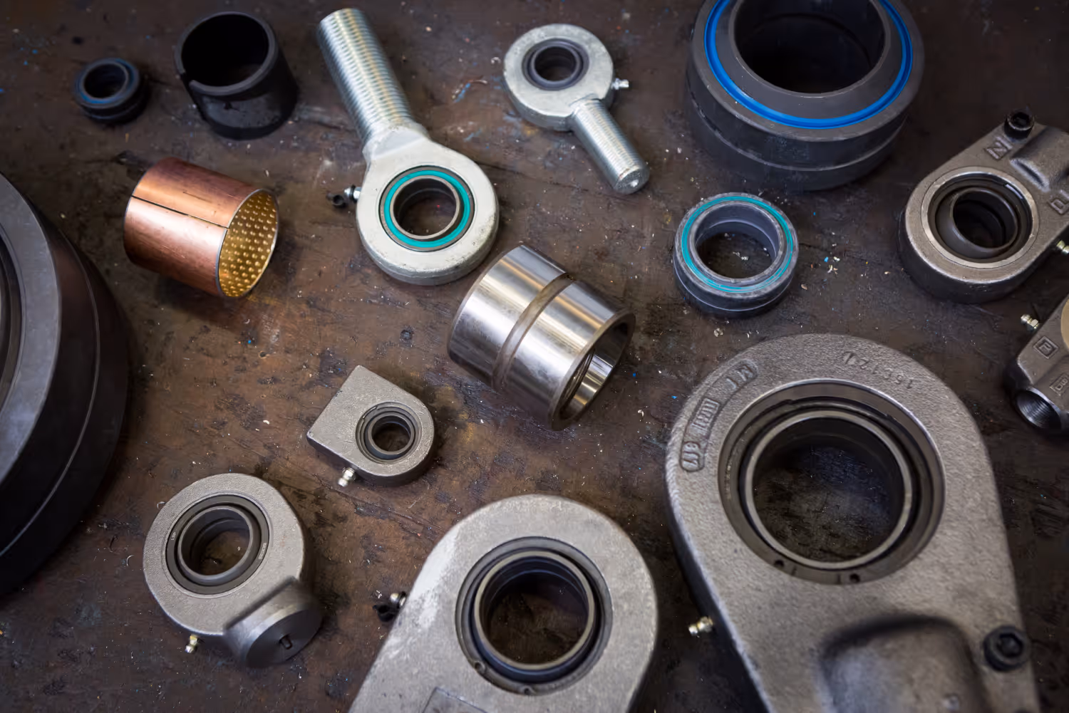 Diverse metalen machine- en lageronderdelen liggen op een werkbank.