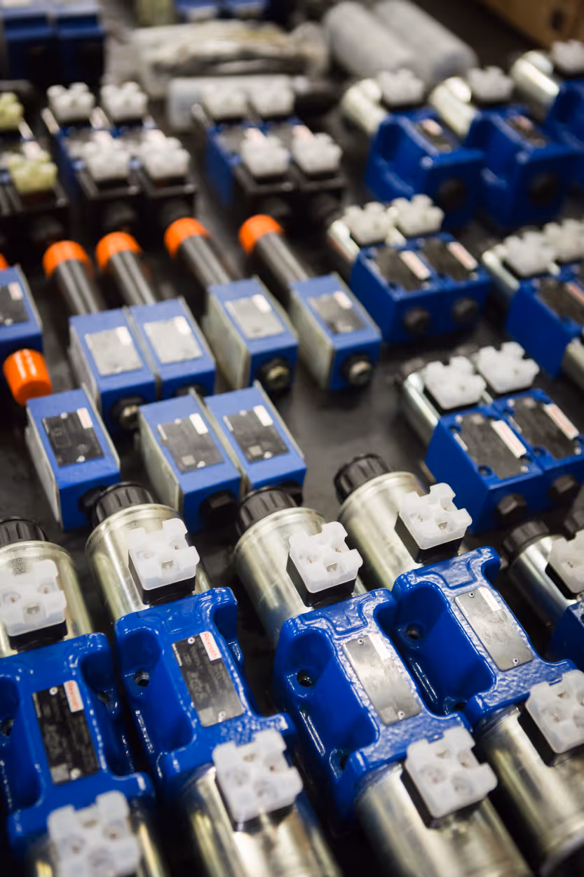 Rijen industriële blauwe en zilveren hydraulische kogelkraankleppen op een rek.