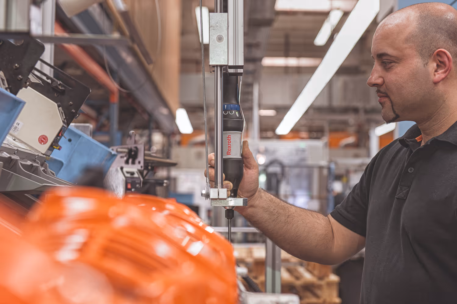 Een man bedient een elektrisch gereedschap in een industriële werkplaats.