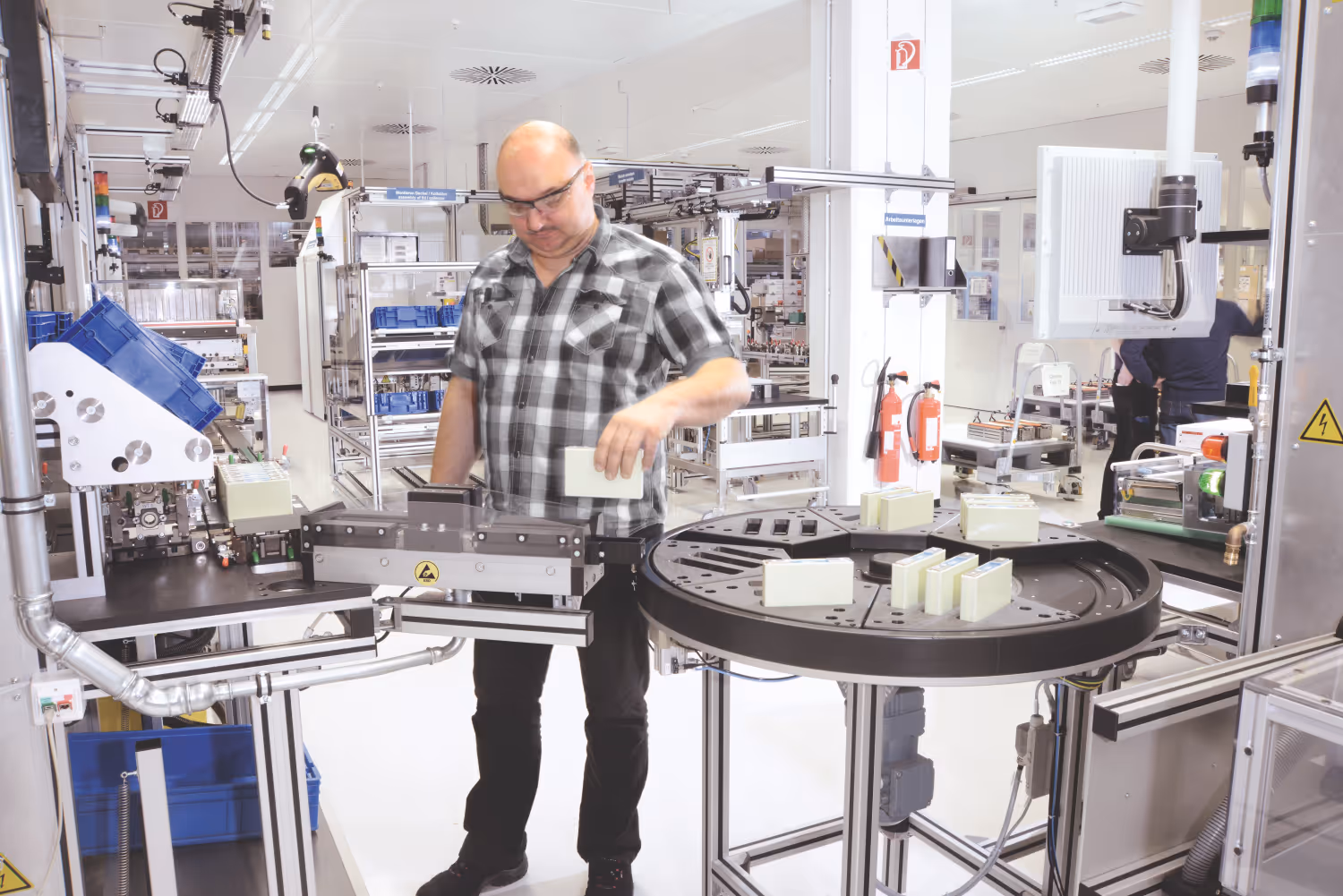 Man werkt aan een automatische productielijn in een schone, goed verlichte fabriekshal.