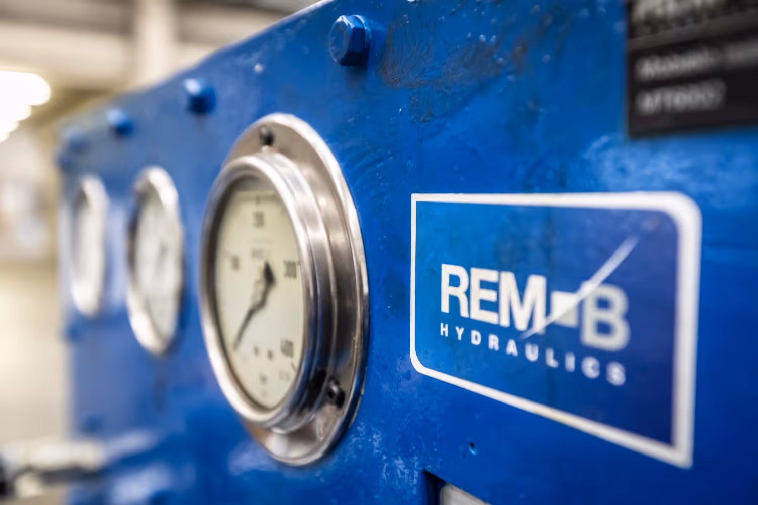 Blauw hydraulisch paneel met meters en een REM-B Hydraulics logo.