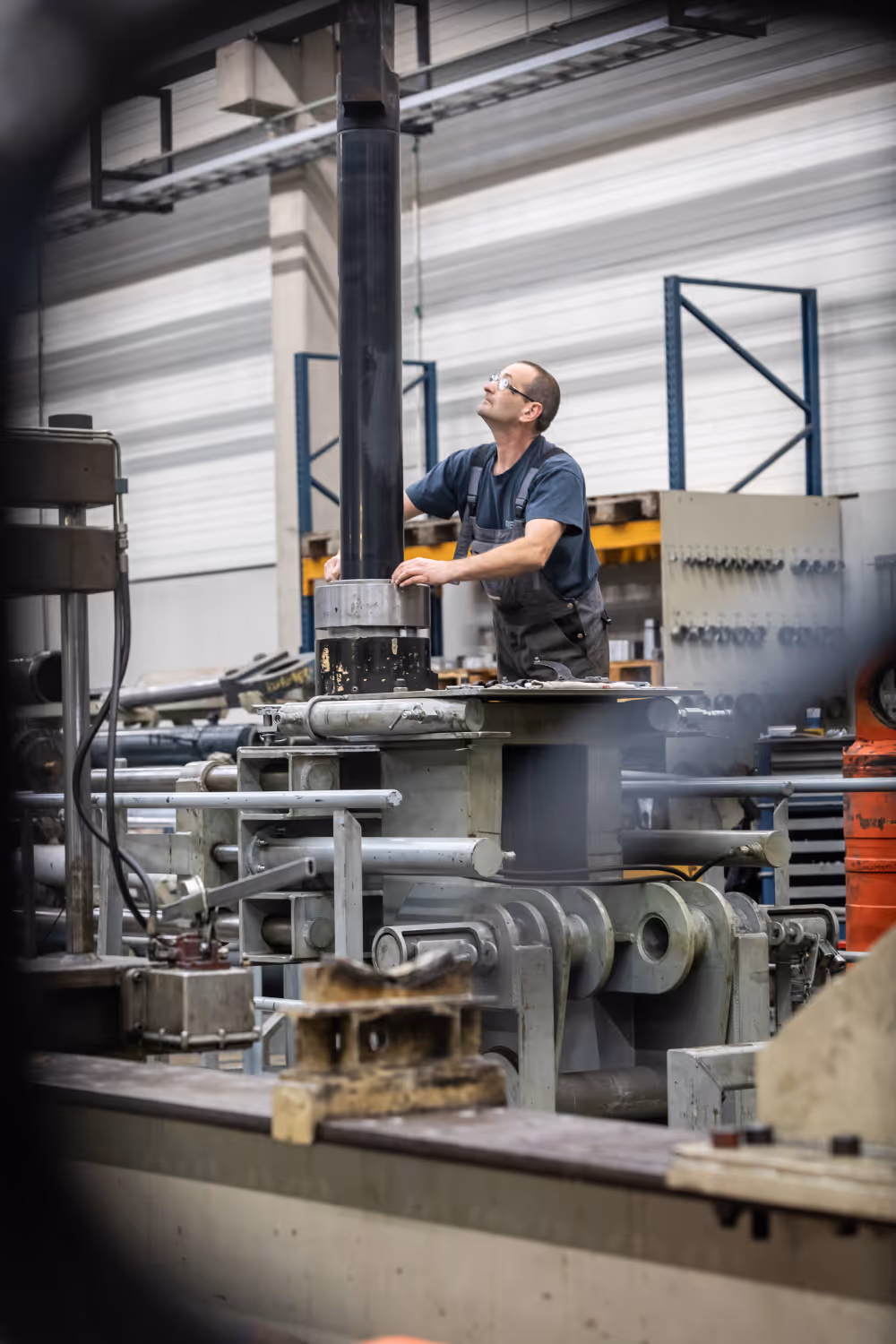 Technicus die een groot industrieel machineonderdeel in een fabriek inspecteert en aanraakt.
