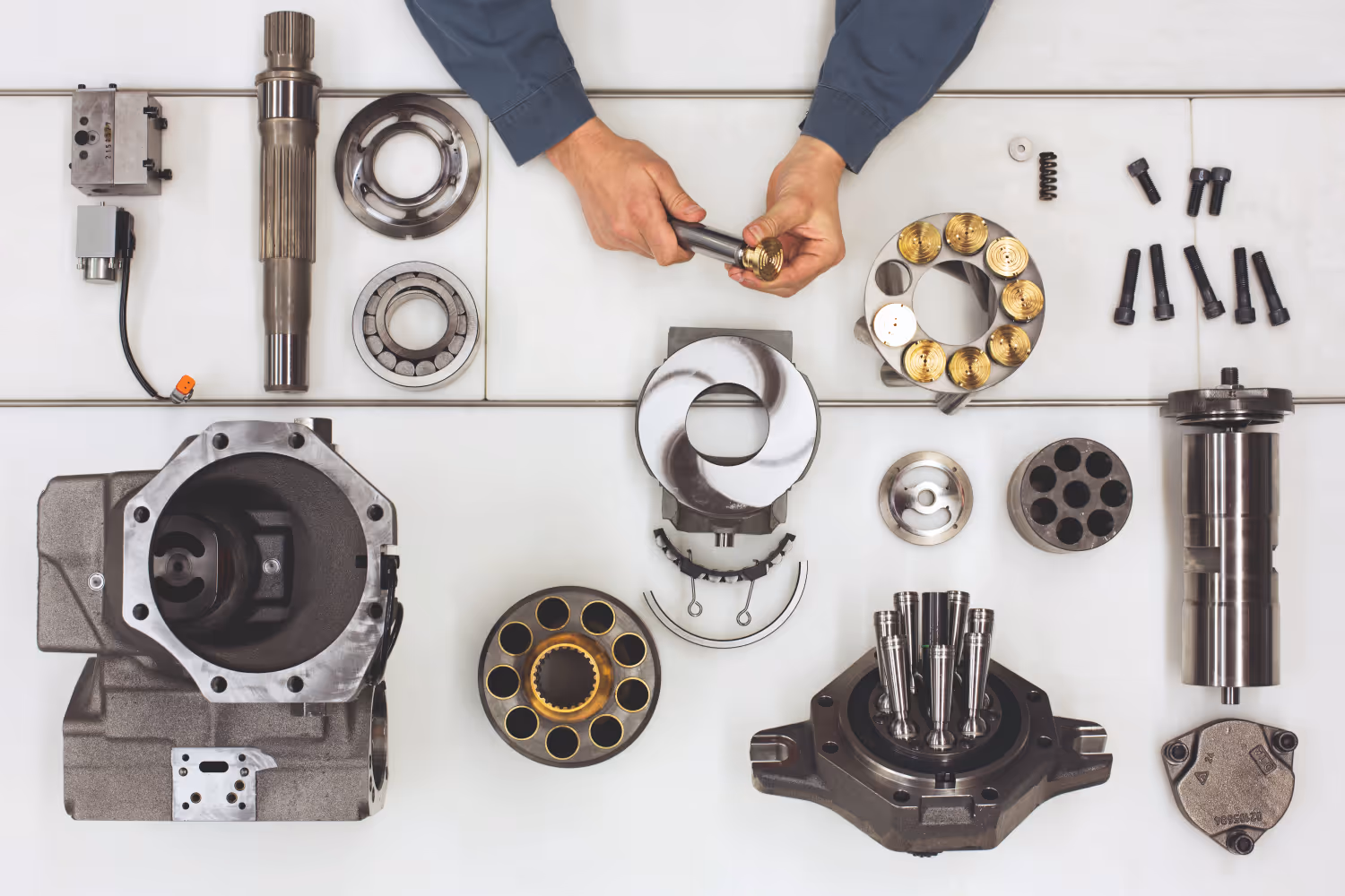 Verspreide metalen onderdelen voor mechanische of hydraulische assemblage op een witte ondergrond.