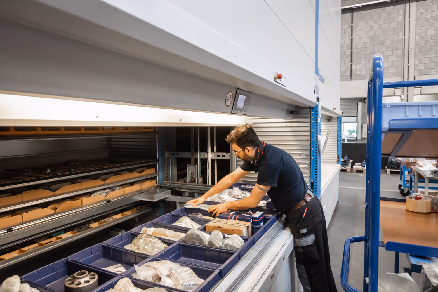 Man in werkplaats controleert dozen in een geautomatiseerd opslag- en ophaalsysteem.