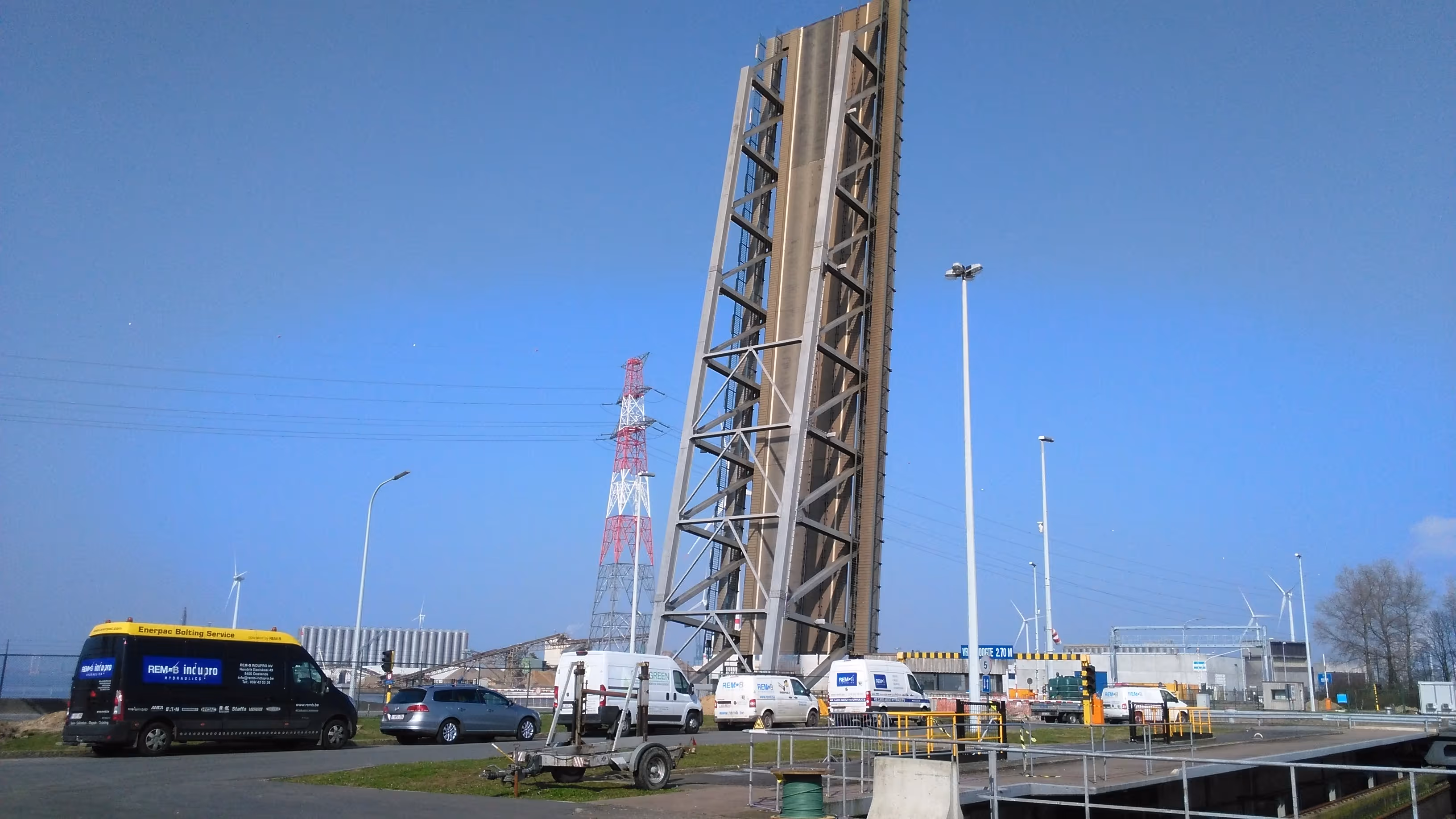 Openstaande ophaalbrug met voertuigen en windmolens op heldere dag.