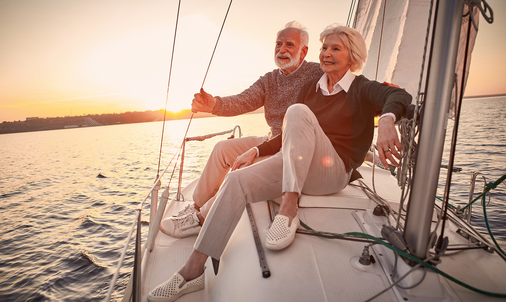 Older couple sail on a boat during sunset and enjoy their retirement after selling the business