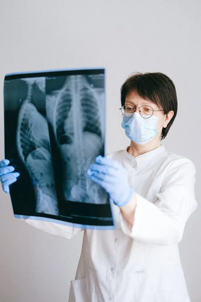 Doctor with mask holding and looking at a bone scan