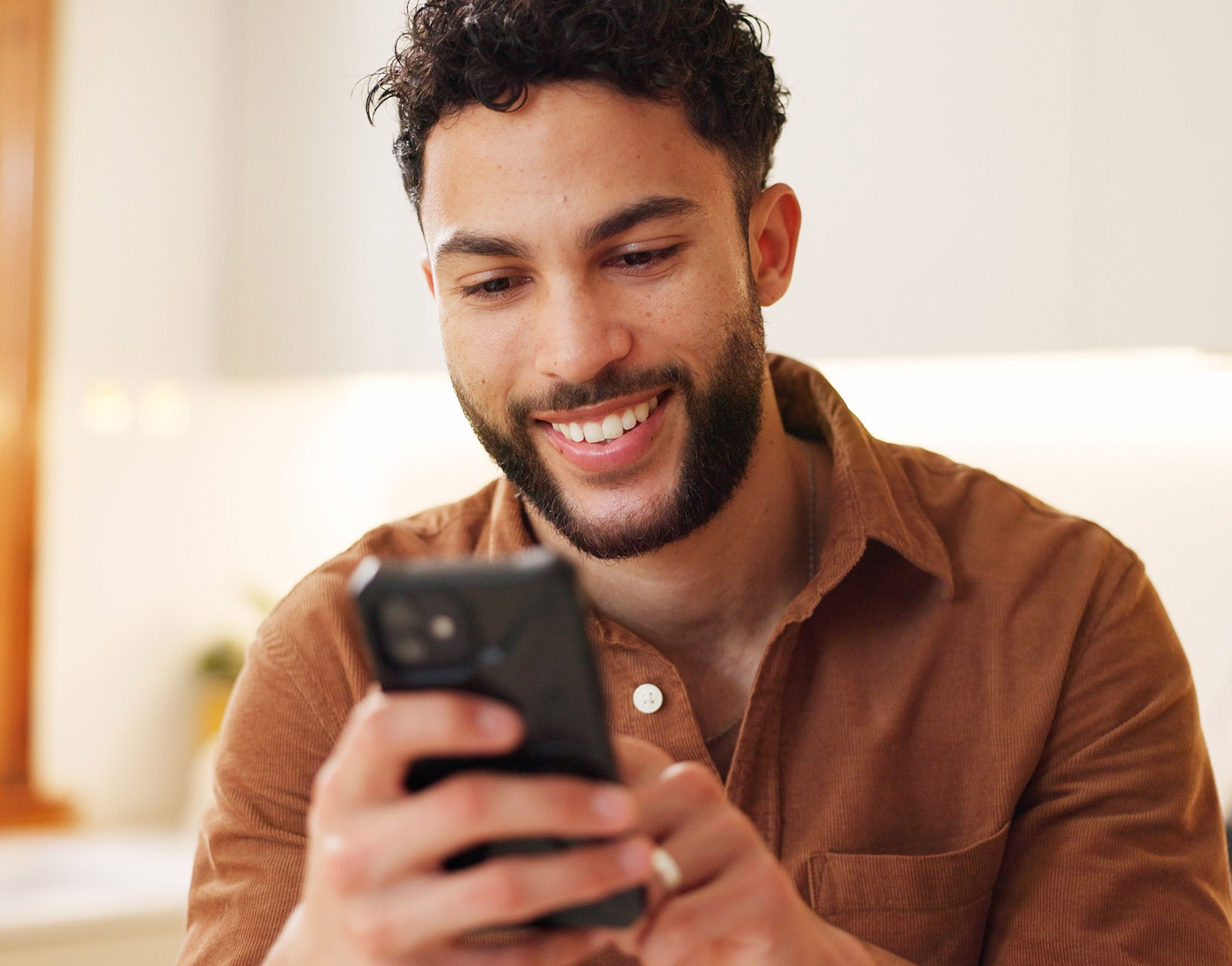 A man smiling while using his phone