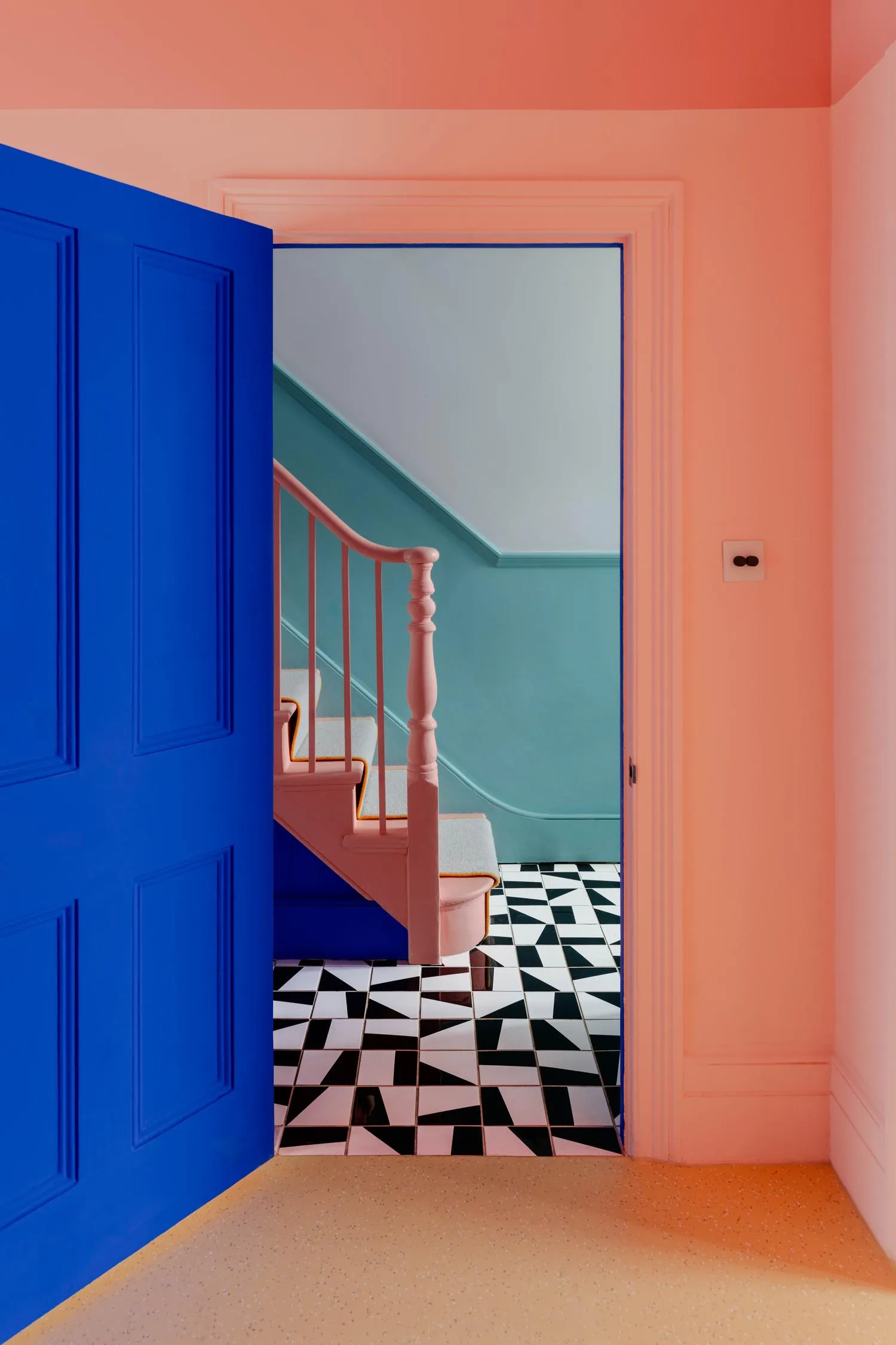 Interior photo looking into the corridor space with a staircase through a blue doorway. By Office S&M, RIBA Chartered Architectural Practice in London.