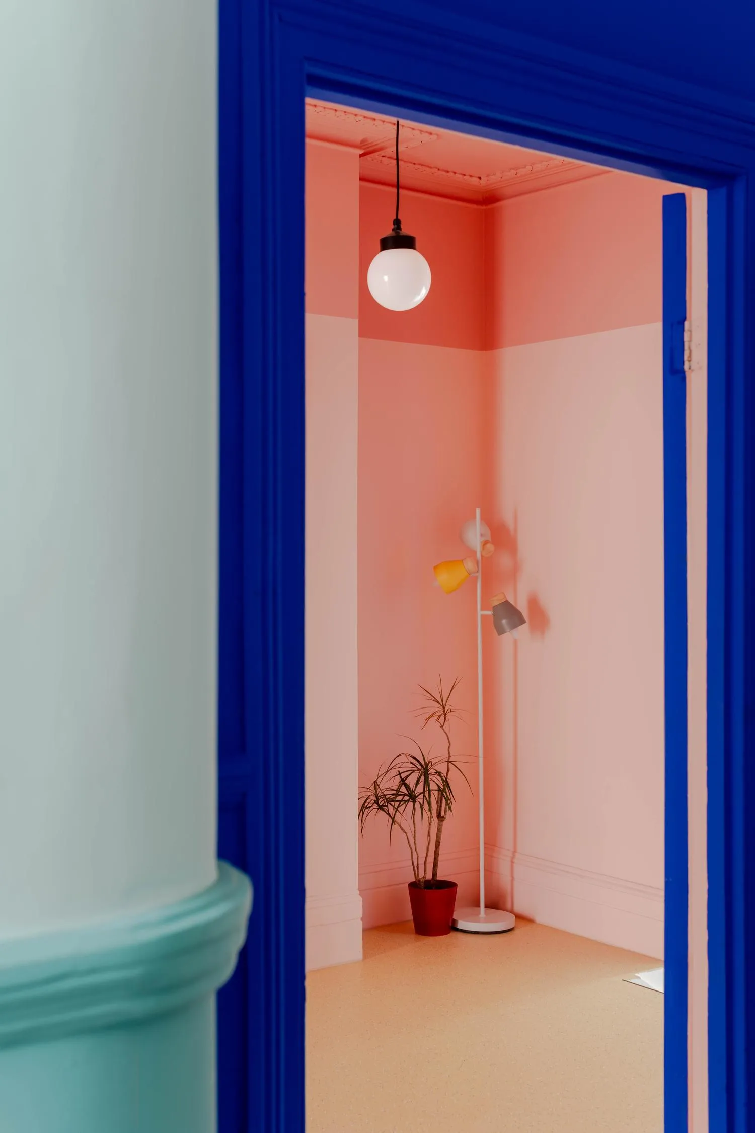 Zoomed in detail photo showing the space in warm orange hues, against the foreground of blue doorway and green wall. By Office S&M, RIBA Chartered Architectural Practice in London.